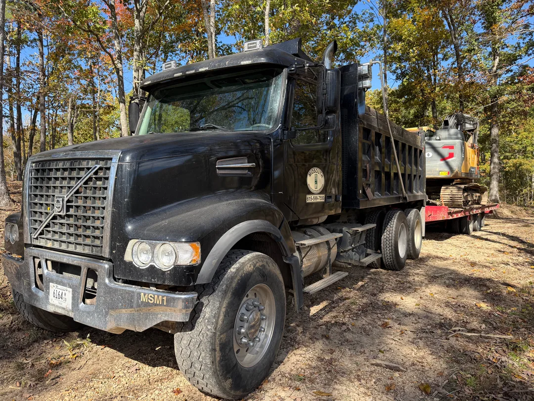 Dump truck staged on a wooded job site
