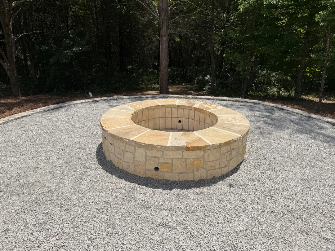 Circular stone fire pit set in a gravel surround