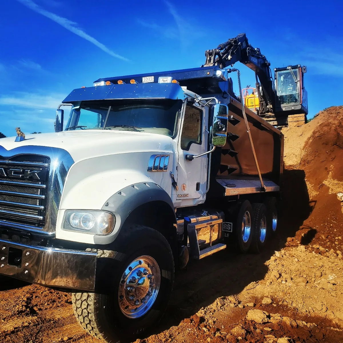 Dump truck and excavator moving dirt on a land clearing job